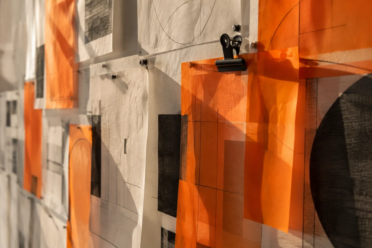 Orange sketches and drawings pinned to a wall